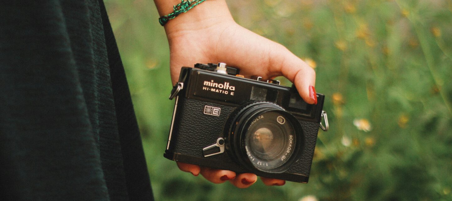 A hand holding a camera in a natural environment