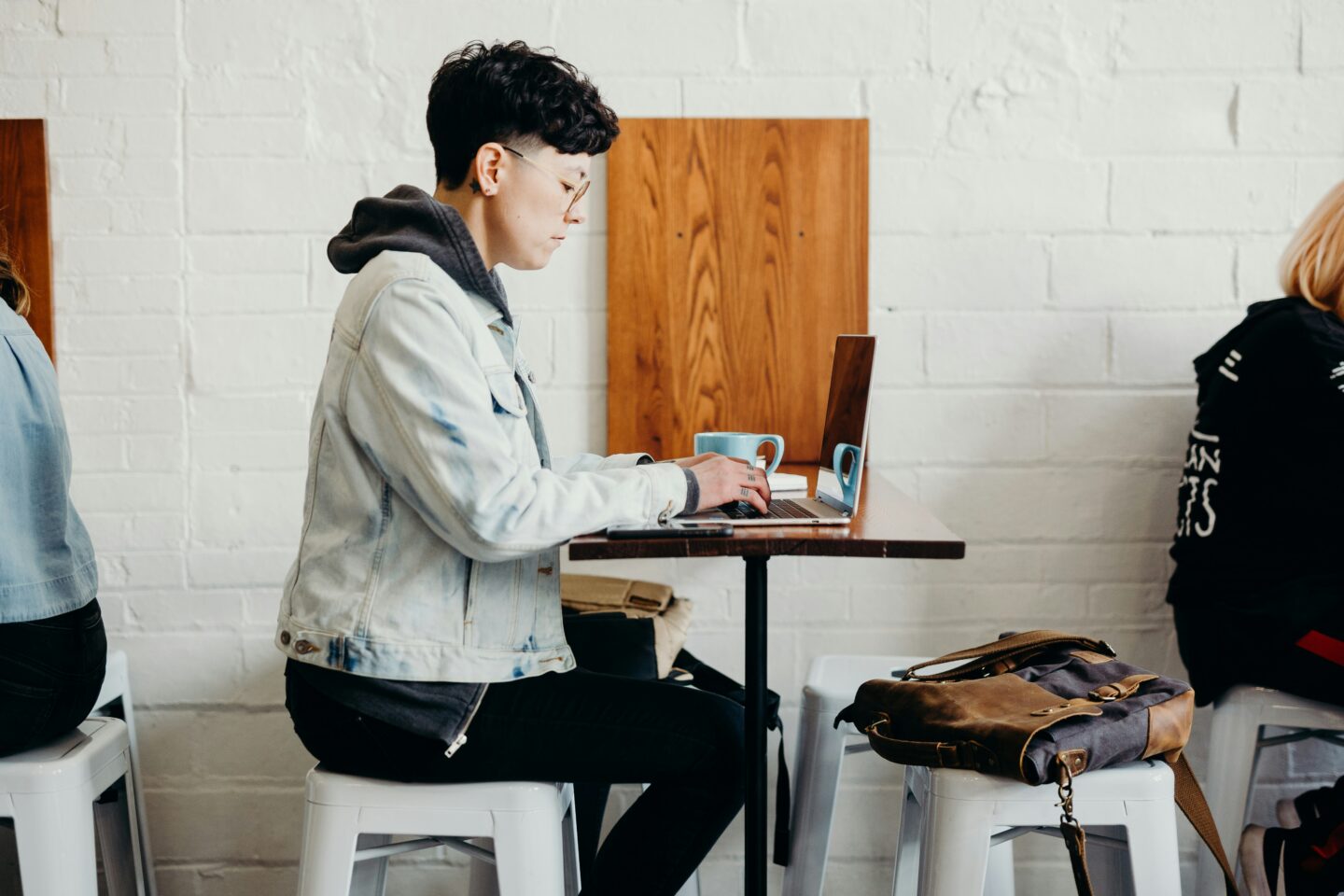 A person seated in a cozy café, focused on their laptop, surrounded by a warm ambiance of coffee cups and a relaxed atmosphere, capturing the essence of productive remote work.