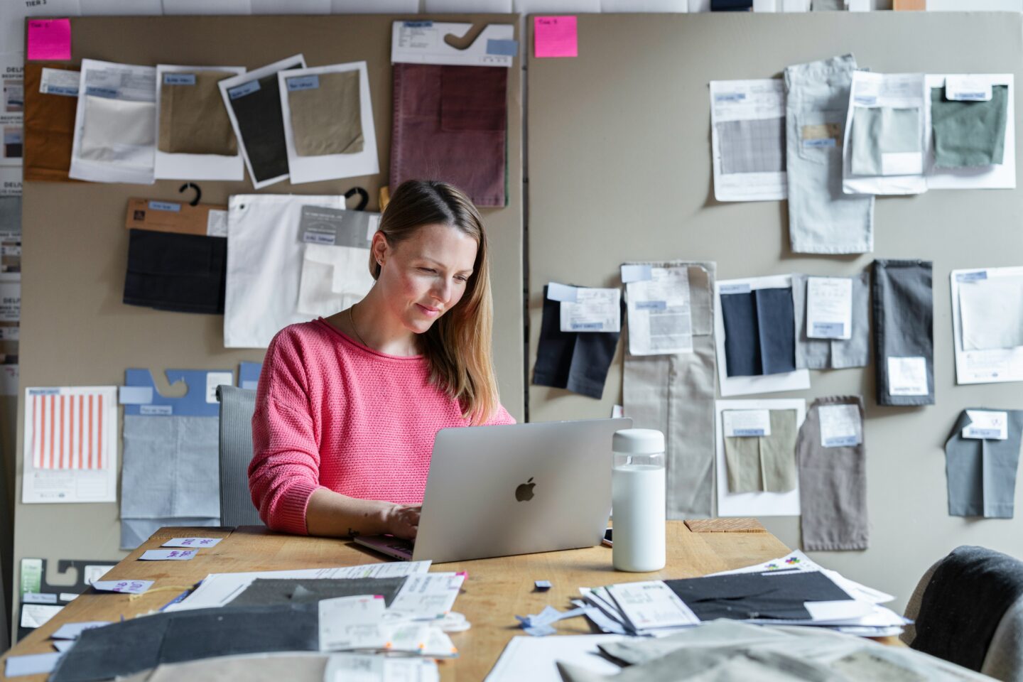 Fashion designer in her workshop, creating an online portfolio to showcase her outfits.