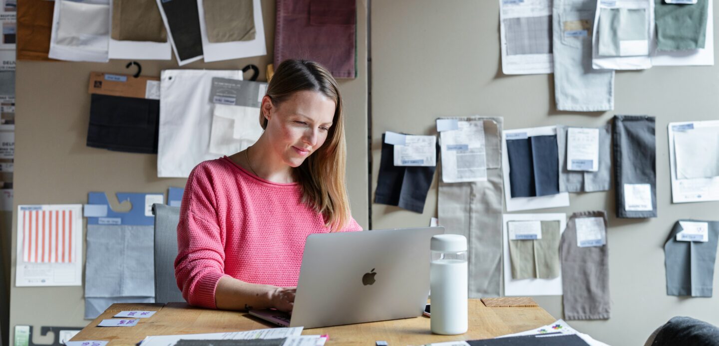 Fashion designer in her workshop, creating an online portfolio to showcase her outfits.