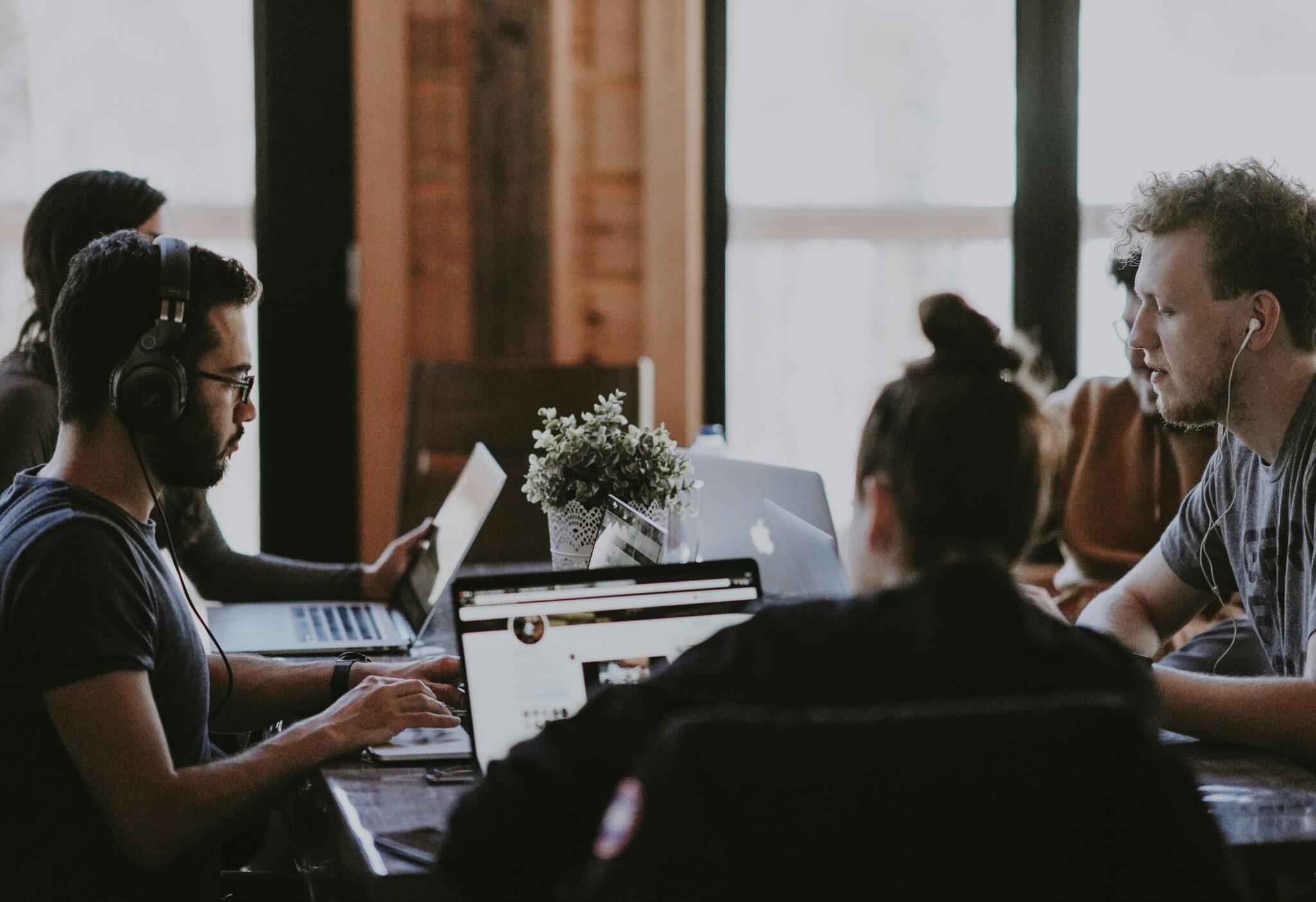 Group of entrepreneurs collaborating on laptops and tablets, focusing on building their websites and enhancing their digital presence in a modern office setting.