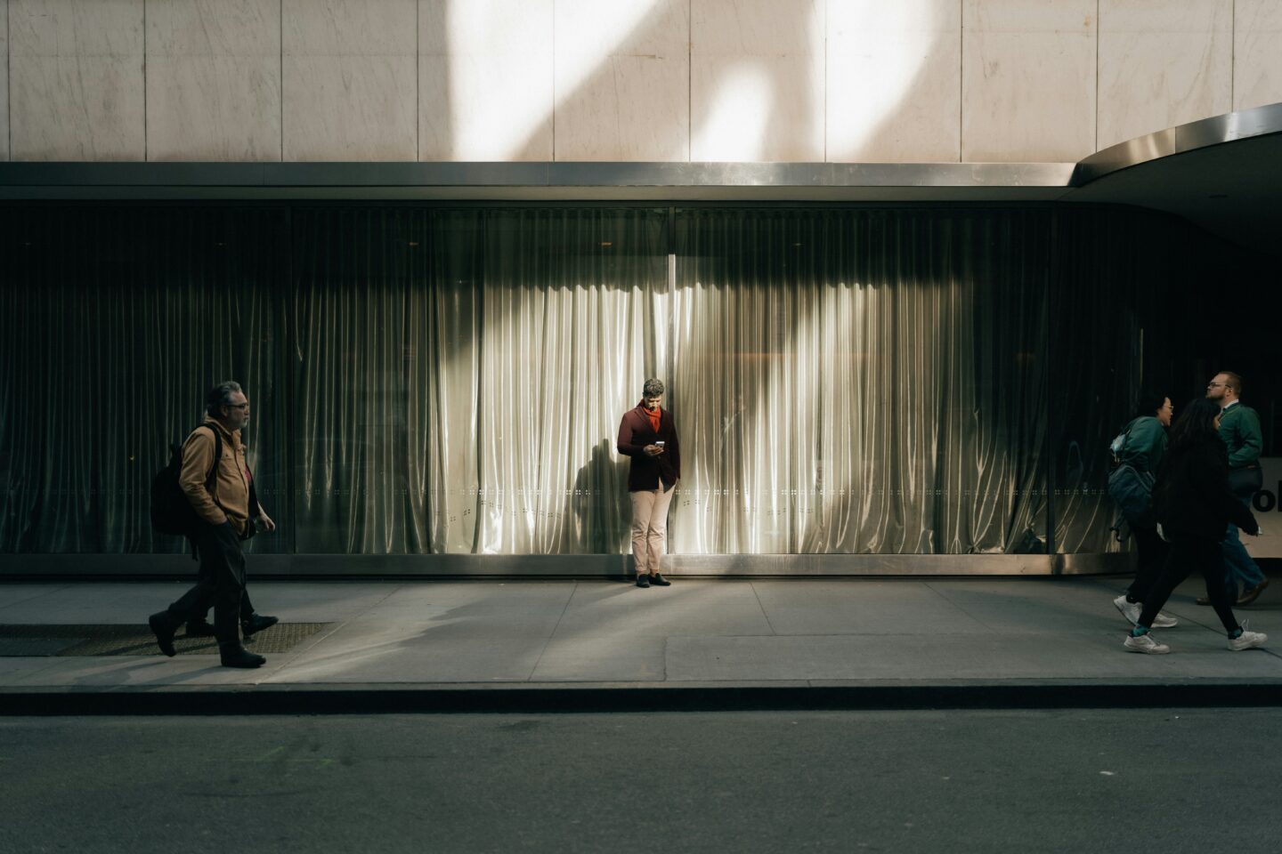 Man standing scrolling on his phone in a busy city